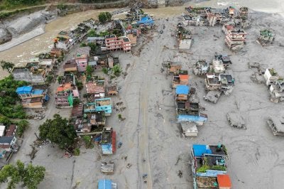 This aerial photograph shows houses covered heavily in sludge in the aftermath of flash floods at Devighat in Nepal's Nuwakot district on August 29, 2026. Nearly 3,000 people were still missing on August 29 and 633 confirmed dead after flash floods and landslides hit the Nepal-Tibet border. (Photo by Manan VATSYAYANA / AFP)