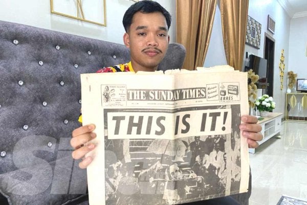 Anak sulung Noorulhuda, Muhammad Nabil Asyraf, 20, menunjukkan akhbar lama berusia 69 tahun yang merekodkan detik bersejarah pengisytiharan kemerdekaan negara pada 1957.