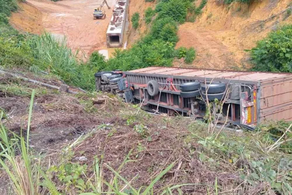 Pemandu treler maut selepas kenderaan berat berkenaan dipercayai terbabas dan jatuh gaung sedalam 20 meter di Lebuh raya Gua Musang - Kota Bharu, berhampiran Ladang Selasa di Gua Musang pada Ahad. - Foto:JBPM