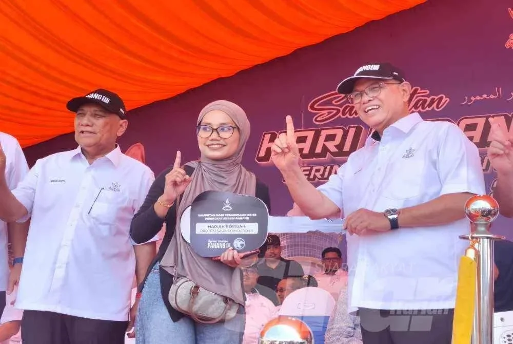 Nurul Atirah (tengah) menerima replika kunci daripada Wan Rosdy selepas diumumkan sebagai pemenang hadiah utama sempena Sambutan Hari Kebangsaan 2026 Peringkat Negeri Pahang pada Isnin.