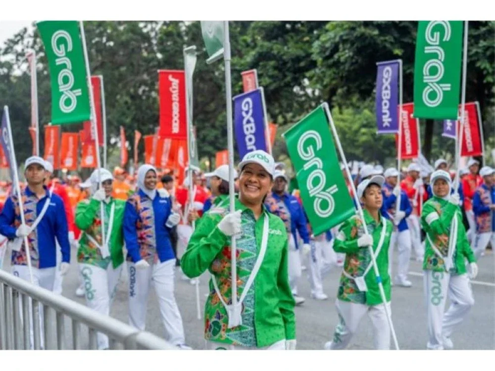 Syuhainie (depan, dua dari kiri) melangkah penuh semangat ketika menjadi sebahagian daripada kontinjen Grab Malaysia pada perarakan Hari Kebangsaan 2026 pada Ahad.