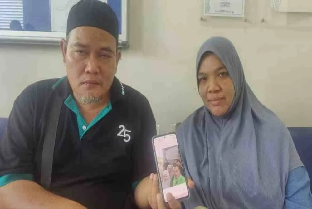 Norramin dan isterinya, JamiatulHuda Ishak, 45. Menunjukkan gambar keluarga termasuk Muhammad Anas (belakang sekali) ketika ditemui di Unit Forensik Hospital Tanjong Karang di sini pada Selasa.
