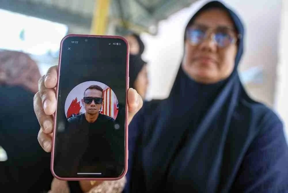 Kakak mangsa, Suhailah Mohd Sanin, 51, menunjukkan gambar adiknya, Mohd Sohaizi Mohd Sanin yang maut dalam kejadian dua bot bertembung berhampiran Kuala Sungai Mersing malam tadi, ketika ditemui Unit Forensik Hospital Mersing hari ini. Foto Bernama
