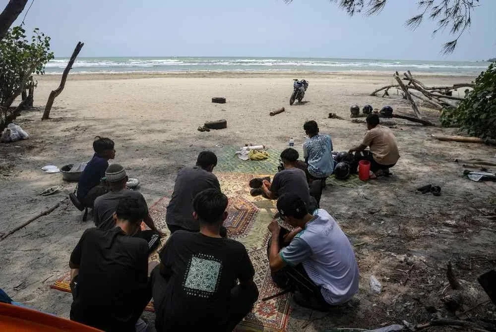 Sekumpulan remaja lelaki menunggu perkembangan operasi mencari dan menyelamat empat rakan mereka yang berusia 16 tahun dan dikhuatiri lemas ketika mandi-manda di Pantai Tanjung Lompat, Tanjung Balau, Penawar, pagi ini. Foto Bernama.
