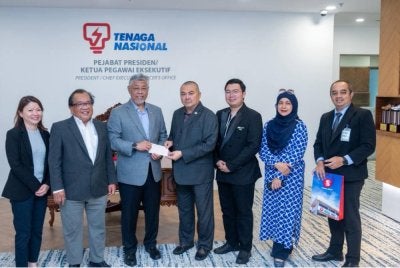 Hisham (empat dari kanan) menyerahkan cek dividen kepada Shamsul (tiga dari kiri) di Menara TNB, Bangsar.
