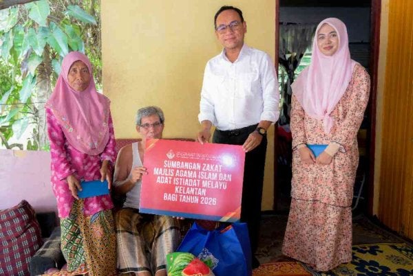 Muhamad Rasani (dua dari kanan) menyampaikan sumbangan MAIK kepada Nurul Atiqah (kanan) serta datuk dan neneknya di rumah mereka di Kampung Tal Tujuh, Pasir Mas pada Rabu.