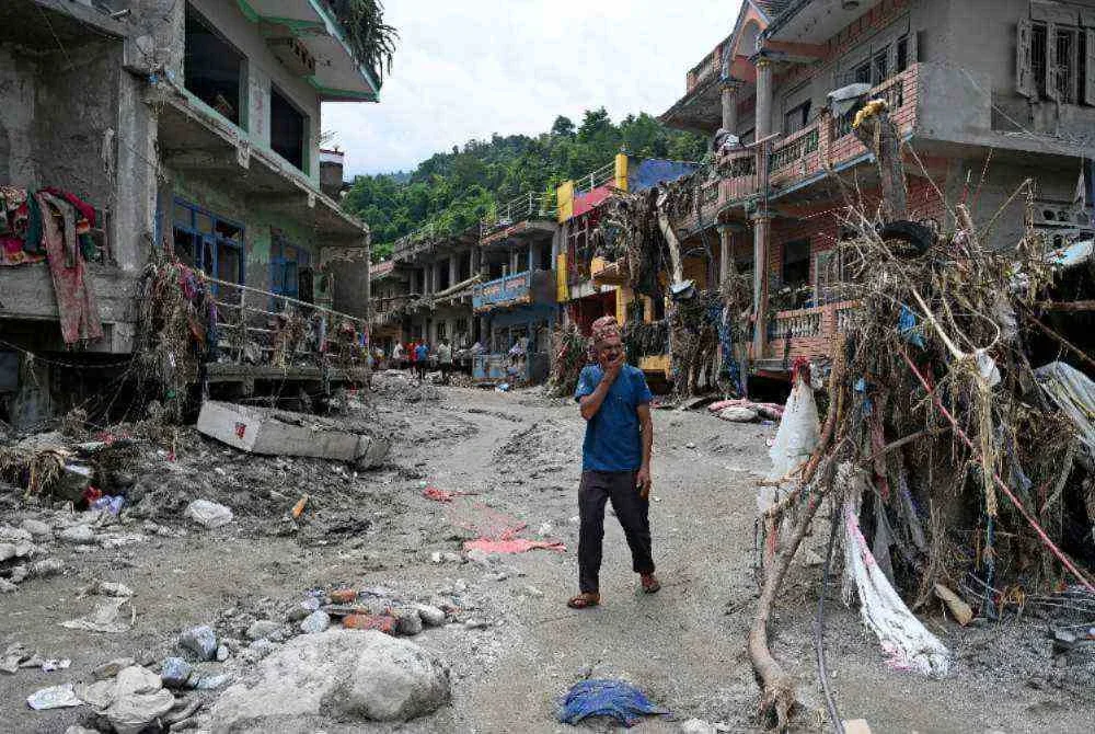 Seorang lelaki berjalan berhampiran rumah yang rosak akibat banjir kilat di Devighat, daerah Nuwakot, Nepal. Foto: AFP