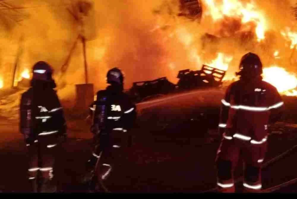 Anggota Bomba dan Penyelamat memadamkan kebakaran dua gudang di sini pada Rabu.