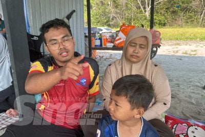 Muhammad Azril Haziq (kiri) dan ibunya setia menunggu perkembangan operasi SAR di Pantai Tanjung Lompat, Bandar Penawar.