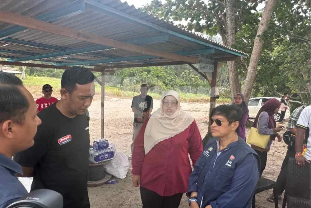 Menteri di Jabatan Perdana Menteri (Undang-Undang dan Reformasi Institusi, Datuk Seri Azalina Othman (kanan) menyantuni Sharizal dan ahli keluarga Muhamad Haiman Fitri yang setia menunggu di Pantai Tanjung Lompat pada Jumaat.