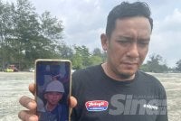 Sharizal menunjukkan gambar anak saudaranya, Muhamad Haiman Fitri yang masih hilang di Pantai Tanjung Lompat.
