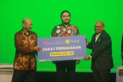 Tengku Amir (tengah) menyaksikan simbolik penyerahan sumbangan zakat perniagaan sempena majlis itu pada Khamis.
