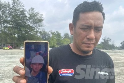 Sharizal menunjukkan gambar anak saudaranya, Muhamad Haiman Fitri yang masih hilang di Pantai Tanjung Lompat.