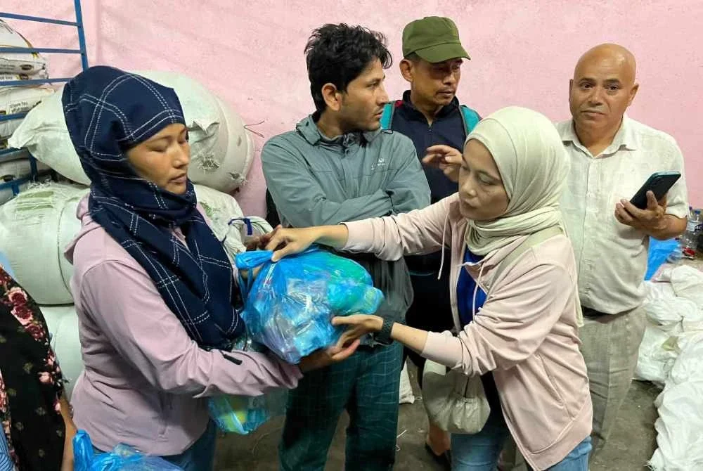 Hani (kanan) menyalurkan sumbangan kepada mangsa banjir di Nepal pada Jumaat sebagai mewakili Team Loe.