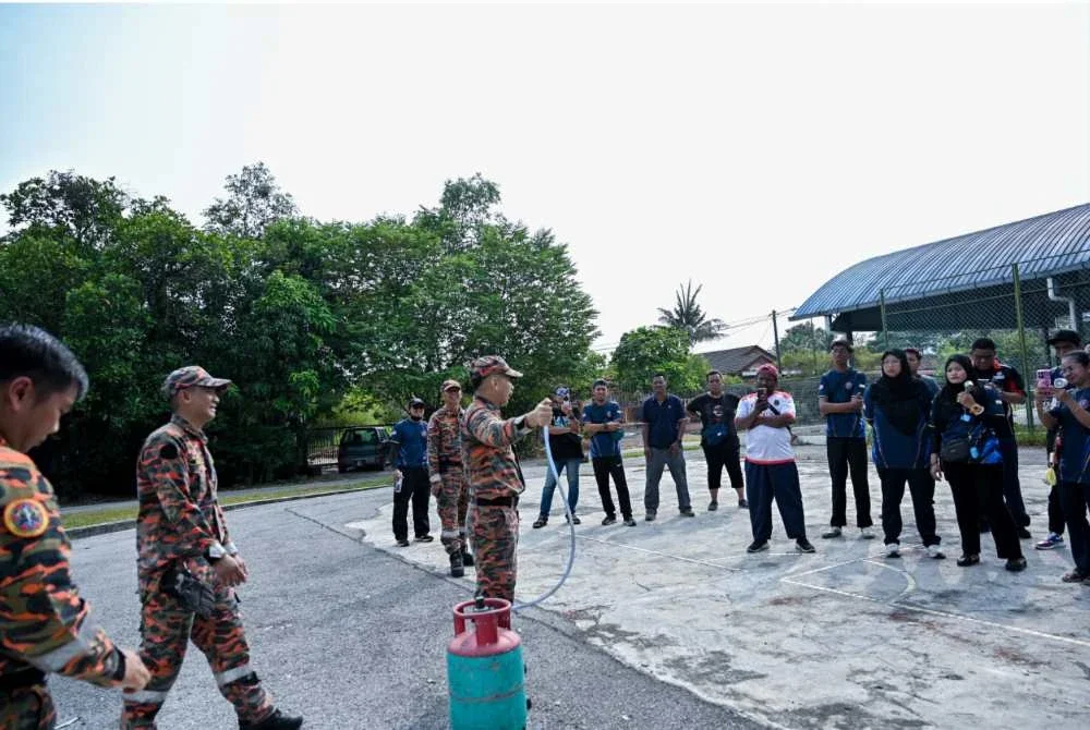 Anggota dan BBP Meru Raya ketika menyampaikan taklimat dan demonstrasi latihan pemadaman kebakaran kepada Pasukan Bomba Komuniti KAMI Gugusan Manjoi.