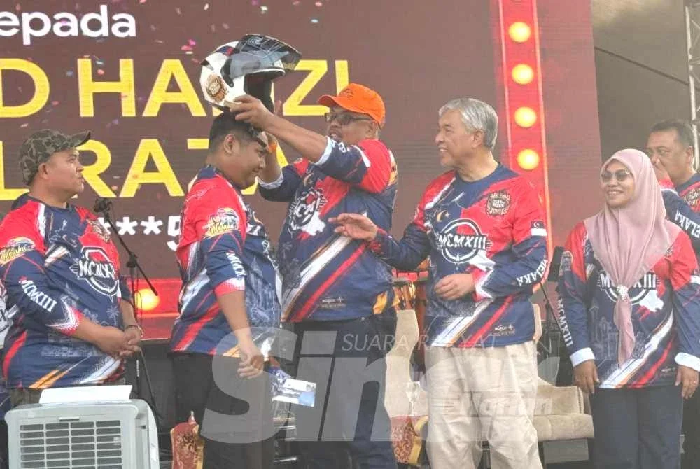 Ahmad Zahid (dua dari kanan) menyaksikan Ab Rauf menyampaikan topi keledar kepada salah seorang pemenang hadiah cabutan bertuah.