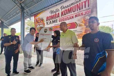 Mohamad Hairul Amir (dua dari kiri) menurunkan tandatangan sebagai gimik perasmian Pasukan Bomba Komuniti KAMI (Komuniti Anak Manjoi Ipoh) Gugusan Manjoi di Dewan Komuniti Sungai Tapah di Ipoh pada Ahad.