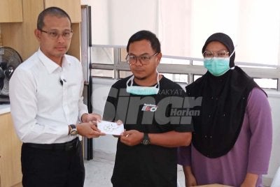 Mohd Fared (kiri) menyerahkan sumbangan Majlis Agama Islam Johor (MAIJ) kepada ibu bapa Haira di HSA Johor Bahru.