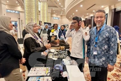 Ahmad Jailani (dua dari kanan) melawat ke reruai pameran pemain industri yang menyertai simposium. 