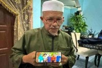 Kamarudin Salleh, bapa kepada salah seorang penumpang helikopter yang terhempas berhampiran Long Lellang, Sarawak, Dr. Ainul Baroah, menunjukkan gambar anaknya (dua, kiri) bersama ahli keluarga ketika ditemui pemberita di kediamannya. Foto Bernama