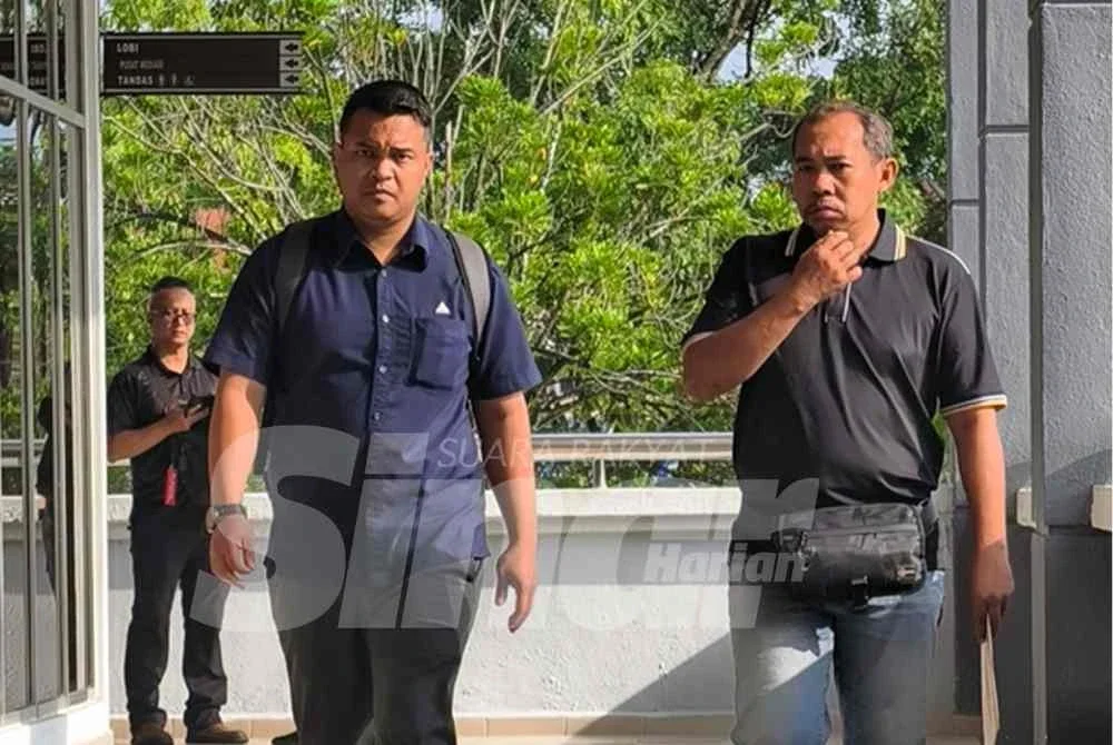 Mohd Suhaimi (kanan) diiring pegawai MCMC di Mahkamah Seremban