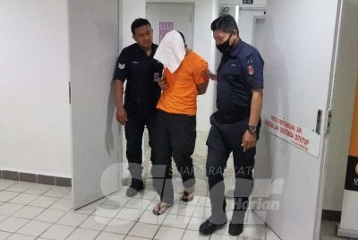 Tertuduh (tengah) ketika dihadapkan di Mahkamah Sesyen Kuala Terengganu pada Khamis.