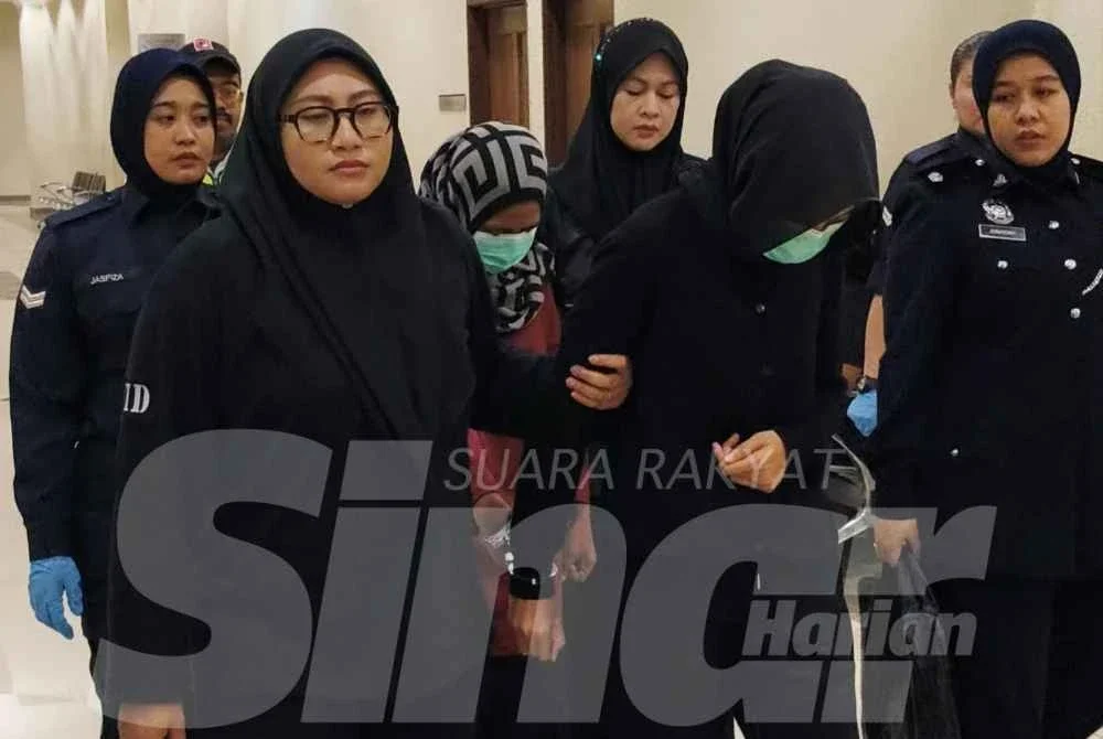 Zairifah (depan) dan Norlida diiringi anggota polis ketika dibawa untuk sebutan kes di Mahkamah Sesyen pada Jumaat.