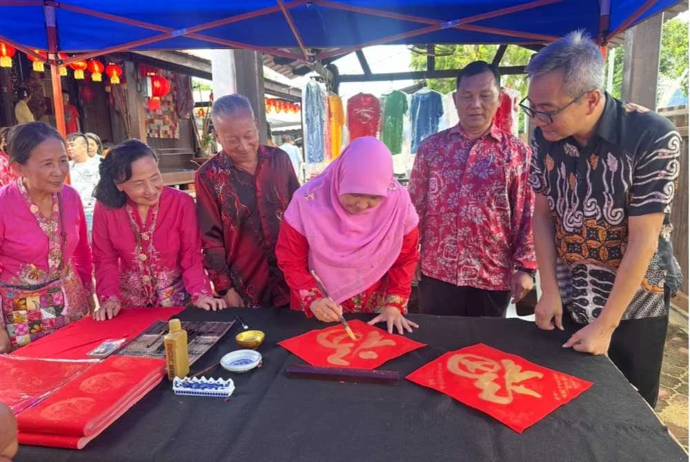 Dr Hafidzah (tiga dari kanan) mencuba seni kaligrafi Cina sambil diiringi Kham Hong (dua dari kanan).