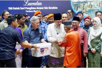 Anwar (tengah) menyampaikan sumbangan kepada mangsa kebakaran Kampung Numbak di Dewan Serbaguna Damai. Foto Bernama