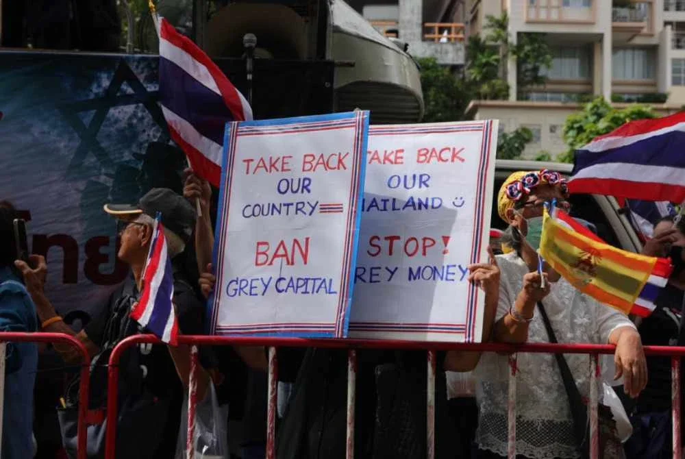Penunjuk perasaan mengangkat sepanduk ketika menyertai demonstrasi membantah dakwaan pengambilan tanah oleh warga asing di hadapan Kedutaan Israel di Bangkok pada Khamis. - FOTO: The Thaiger
