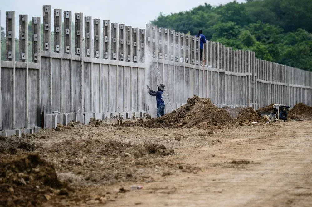 Pekerja membina sebahagian pagar sempadan. FOTO: AFP