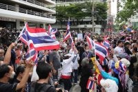 Penunjuk perasaan mengibarkan bendera Thailand ketika menyertai demonstrasi di Bangkok.