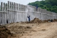 Pekerja membina sebahagian pagar sempadan. FOTO: AFP