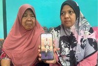Samsiah (kiri) menunjukkan gambar Mohamad Shahrul Azizi yang maut dalam nahas di Jalan Bukit Kelicap, Tanjung Laboh, Batu Pahat pada Jumaat.