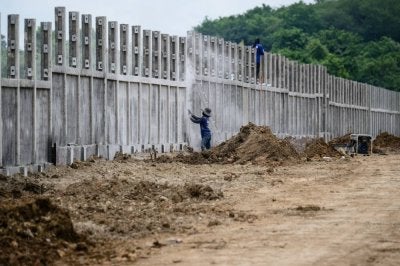 Pekerja membina sebahagian pagar sempadan. FOTO: AFP