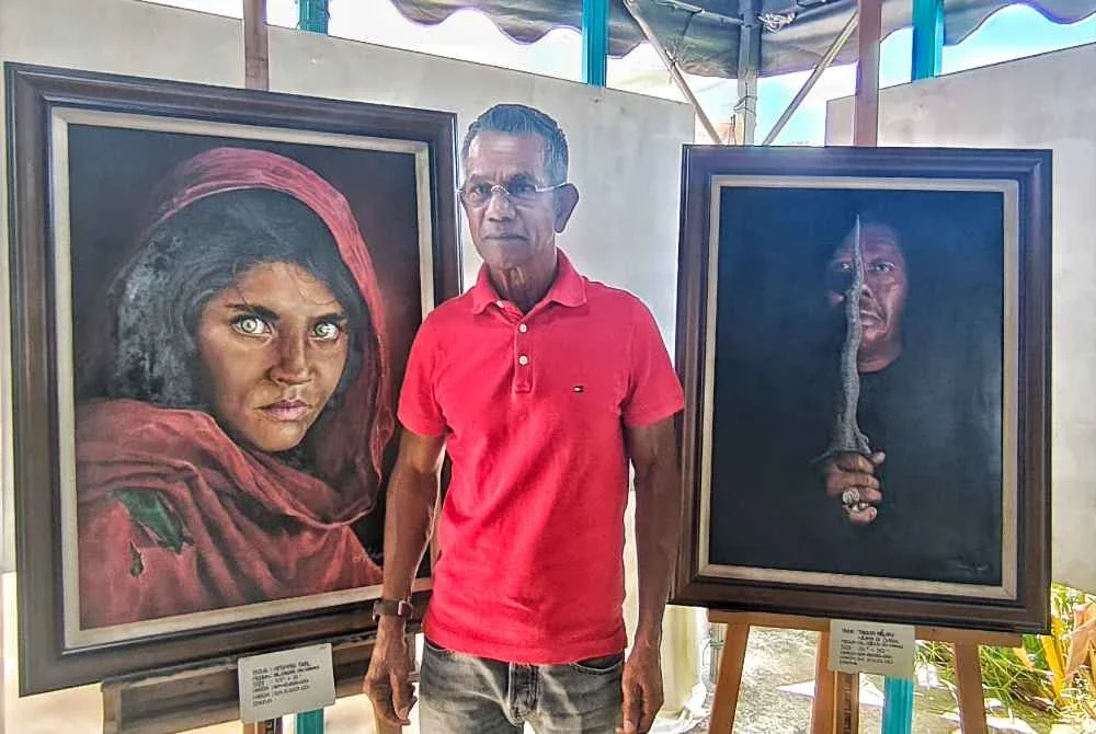 Ismail Hyatt berdiri di antara dua karya lukisan potret tumpuannya yang dipamerkan untuk jualan.