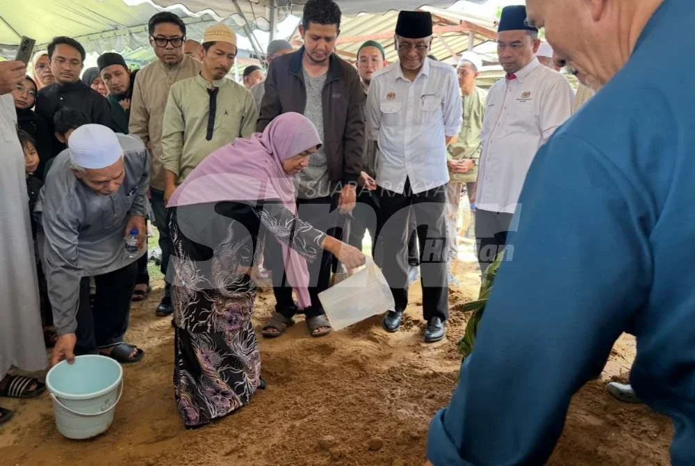 Ibu arwah, Rogayah Mohd Nor menyiram air ke pusara anaknya.
Foto: ADILA SHARINNI WAHID