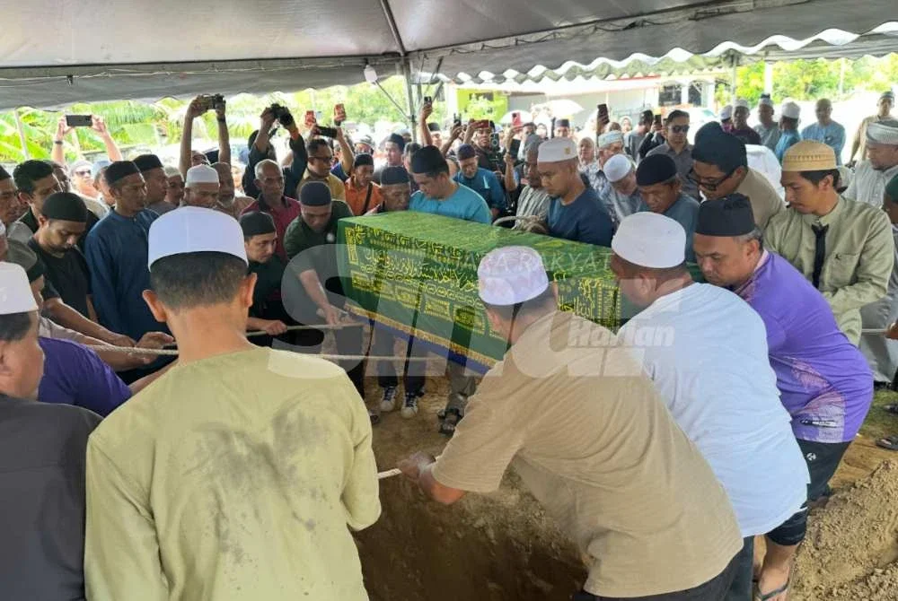 Orang ramai yang membantu menurunkan jenazah Dr Ainul Baraah ke liang lahad. Foto: ADILA SHARINNI WAHID