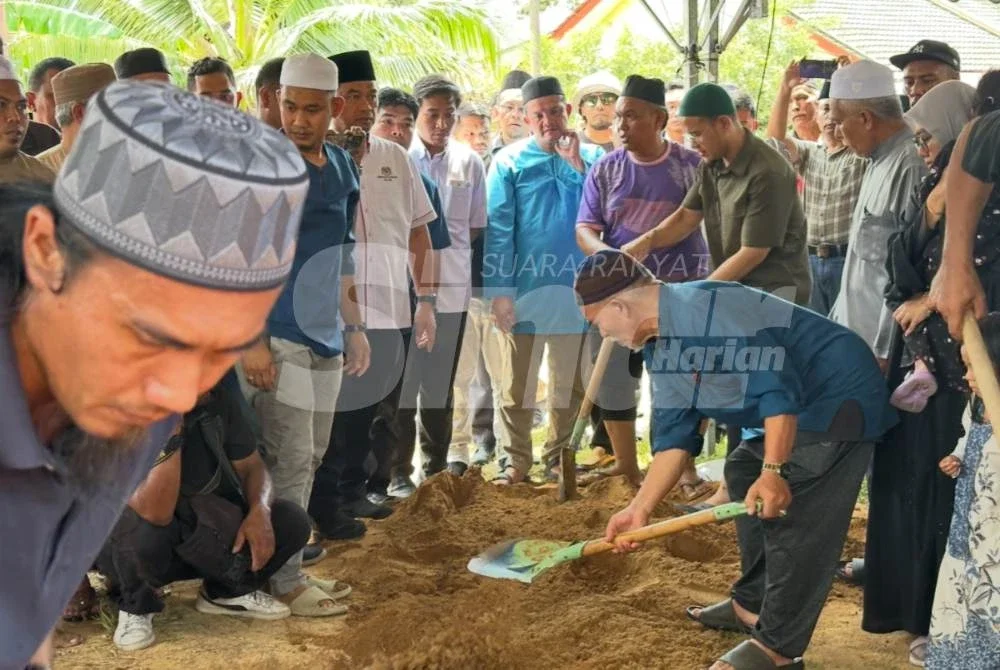 Bapa arwh, Kamarudin Salleh (kanan) membantu mengebumikan jenazah anaknya. Foto: ADILA SHARINNI WAHID