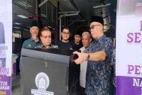 Aminuddin (kanan) menyempurnakan Majlis Sentuhan Kasih Sempena Perasmian Naik Taraf Fasiliti Struktur Bumbung Tambahan di Kompleks Pusat Jagaan Budi Mulia Nurul Huda, Chemor di sini pada Ahad.
