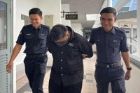 Tertuduh (tengah) mengaku bersalah terhadap pertuduhan dibacakan ke atasnya. 