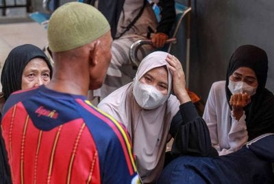 Ahli keluarga dan saudara-mara mangsa feri penumpang Virgo Transport 8 yang karam ketika dalam perjalanan dari Banjarmasin ke Surabaya, menunggu di pelabuhan Banjarmasin, Kalimantan Selatan. - AFP