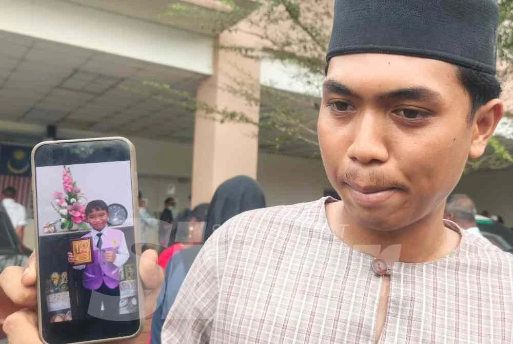 Muhammad Irfan Hafizuddin menunjukkan gambar adiknya semasa ditemui di Jabatan Perubatan Forensik Hospital Sultanah Bahiyah di sini pada Selasa.