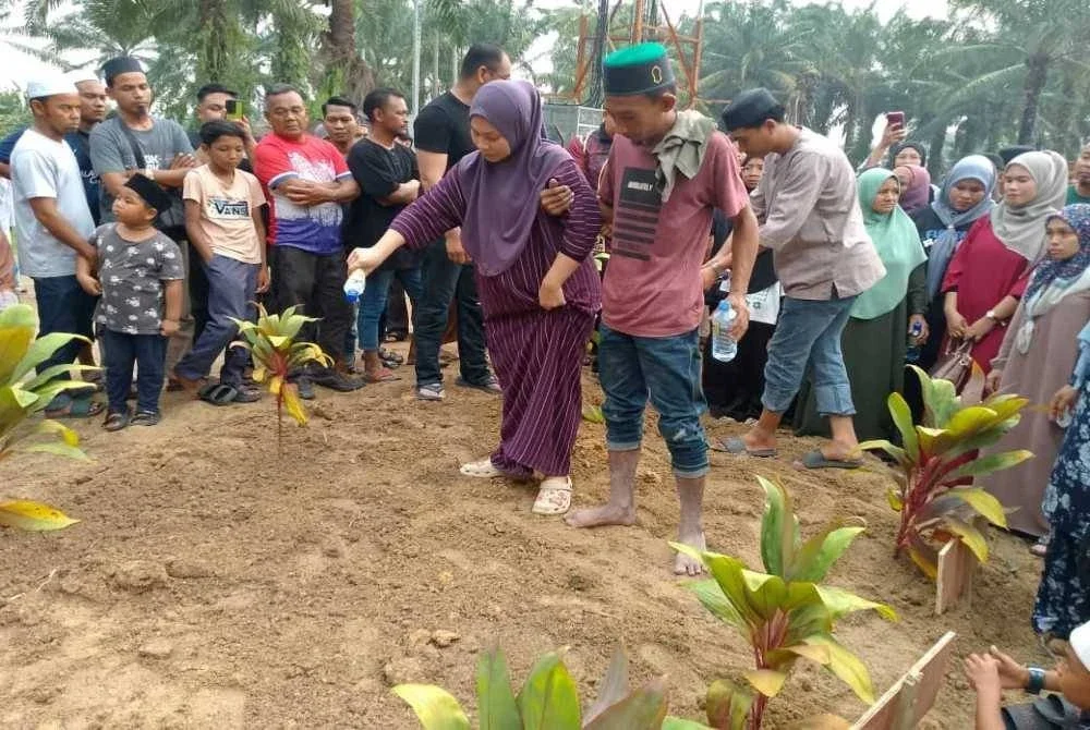 Muhamad Azrin Saidin dan isteri menyiram air di pusara anaknya.