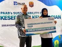 Ir Zulkiflee (kiri) menyampaikan replika cek kepada Nik Hasnas @ Nik Hafizah pada Majlis Perasmian CSR Kelestarian PAAB di SKPH, Kota Bharu pada Selasa.