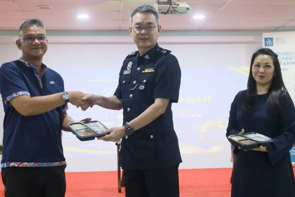Mohd Jazri (kiri) menyerahkan satu unit bento kepada Swee Sake sebagai gimik penyerahan makanan kepada IPDTL sambil disaksikan Mi-Chelle.