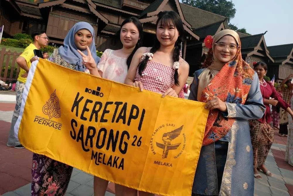 Pelancong asing turut tidak melepaskan peluang bergambar bersama peserta program Keretapi Sarong 2026 bertemakan Sayang Malaysia sempena sambutan Hari Malaysia di pekarangan Muzium Kesultanan Melayu Melaka, Banda Hilir hari ini. - Bernama