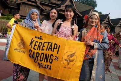 Pelancong asing turut tidak melepaskan peluang bergambar bersama peserta program Keretapi Sarong 2026 bertemakan Sayang Malaysia sempena sambutan Hari Malaysia di pekarangan Muzium Kesultanan Melayu Melaka, Banda Hilir hari ini. - Bernama