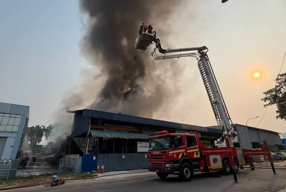 Anggota bomba sedang memadamkan kebakaran kilang pada Khamis.