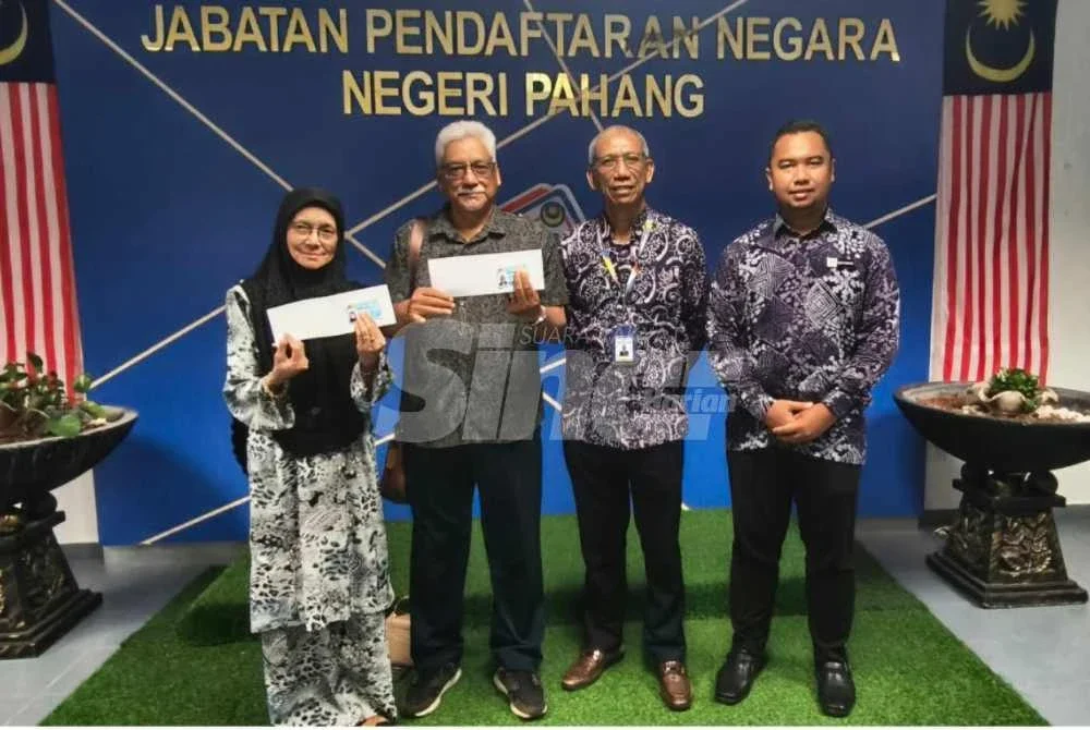 Shafei dan isteri menunjukkan Mykad baharu yang diserahkan Mohammad (dua dari kanan) dalam satu majlis ringkas di JPN Pahang di sini pada Khamis.